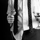 11961754 - image of a man holding a microphone and a drink dressed nicely